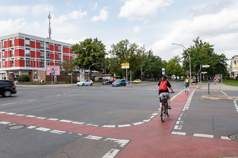 Radfahrerin fährt über Kreuzung mit rot markiertem Radstreifen