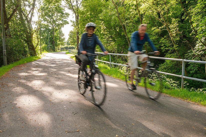 Radfahrende fahren entlang Fließgraben in Pankow