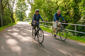 Radfahrende fahren entlang Fließgraben in Pankow