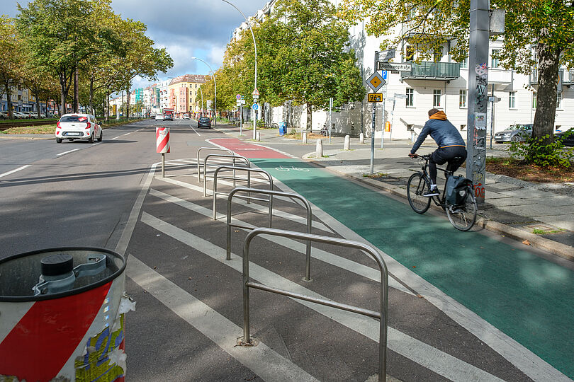 Radfahrstreifen auf der Danziger Straße, der grün eingefärbt ist. Im Vordergrund sind Radabstellbügel.