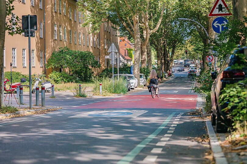Fahrradfahrerin fährt auf einer Fahrradstraße, deren Kreuzung rot beschichtet ist