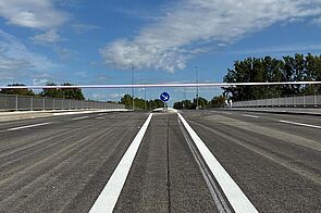 Blick auf den Querschnitt einer neuen Brücke mit Fahrstreifen für Auto- und Radverkehr, Mittelinsel zum Queren