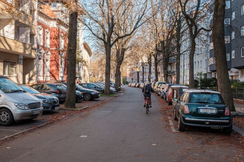 Handjerystraße vor dem Umbau, parkende Autos und eine Radfahrerin auf der Straße