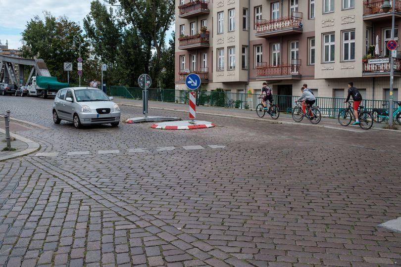 Fahrradfahrende nutzen einen engen Radweg. Im Vordergrund sieht man das Kopfsteinpflaster der Swinemünder Straße.