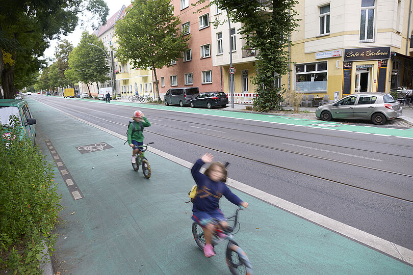 Grünbeschichteter Radfahrstreifen mit Piktogramm und zwei radfahrenden Kindern