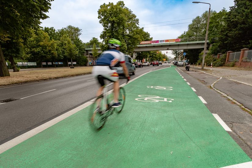 Fahrradfahrer fährt auf einem breiten grün beschichteten Radfahrstreifen