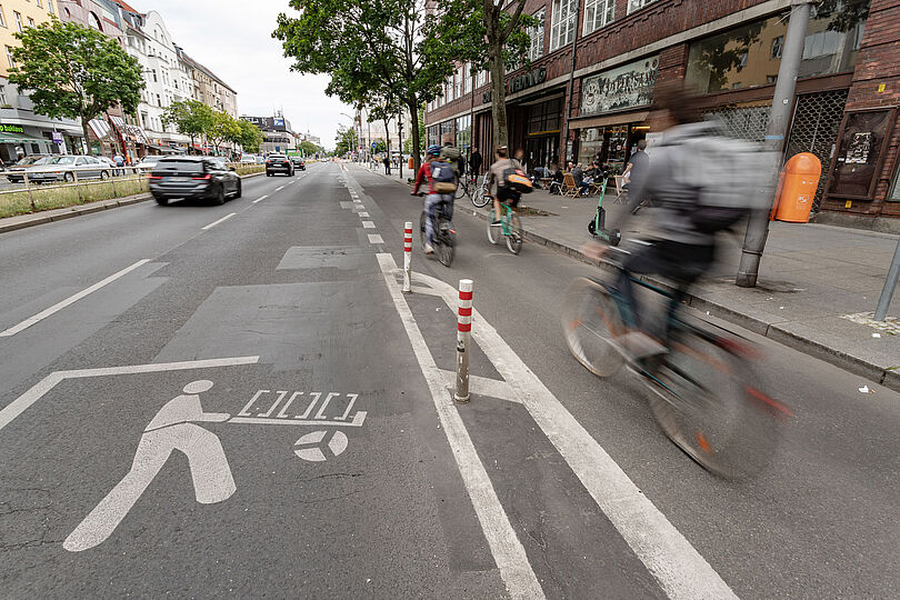 geschützter Radfahrstreifen am rechten Fahrbahnrand, daneben eine markierte Lieferzone, belebte Geschäftsstraße
