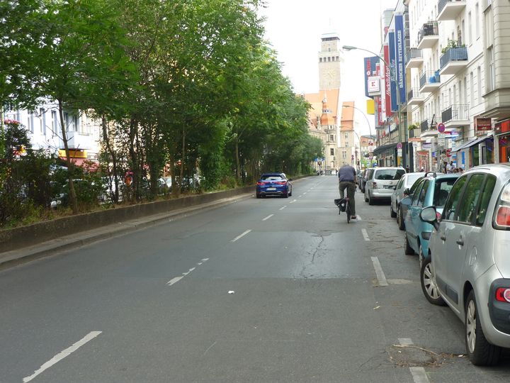 Radfahrer unterwegs auf Karl-Marx-Straße neben parkenden Autos
