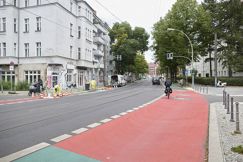 Grün- und Rotbeschichteter Radfahrstreifen in einem Kreuzungsbereich mit einem Radfahrenden.