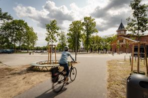 Fahrradfahrerin fährt durch einen Park auf einem asphaltierten Weg