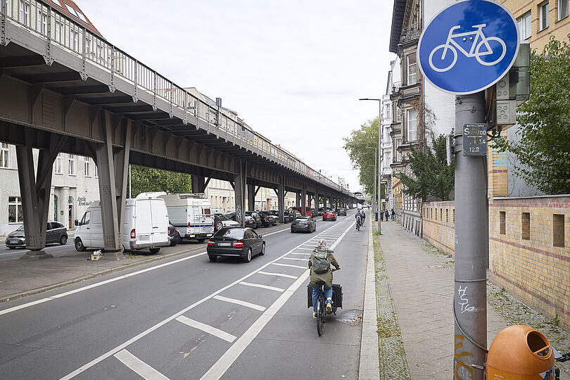 Radfahrstreifen mit Fahrradpiktogrammen, Sicherheitstrennstreifen und Radfahrenden.
