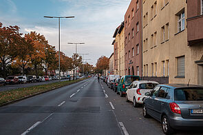 Straße mit zwei Fahrbahnen, rechts parkende Autos