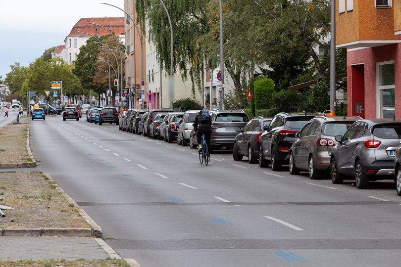 Vorher-Bild: Ein Radfahrer fährt auf der Grunewaldstraße auf der Fahrbahn neben parkenden Autos.
